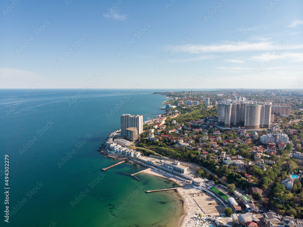 Aerial view of the Black Sea and the city of Odessa. Arcadia beach on a sunny spring day. Seascape and tall houses on the seashore. Vacation and travel in Ukraine