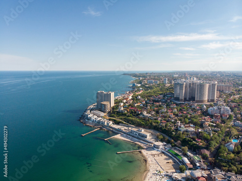 Aerial view of the Black Sea and the city of Odessa. Arcadia beach on a sunny spring day. Seascape and tall houses on the seashore. Vacation and travel in Ukraine