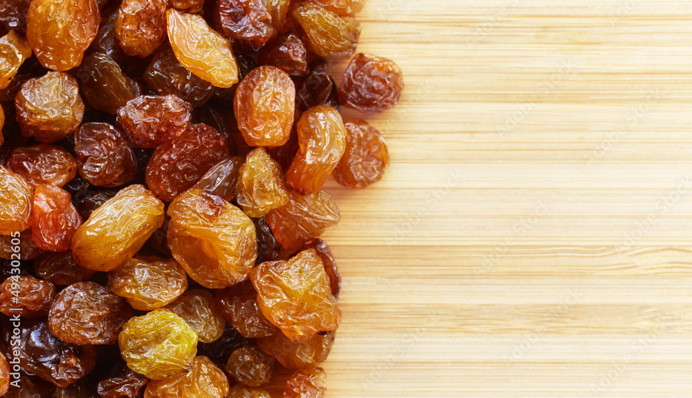 Close up picture of dried small raisins on a wooden background, selective focus. Close up picture of dried small raisins on a wooden background, selective focus.