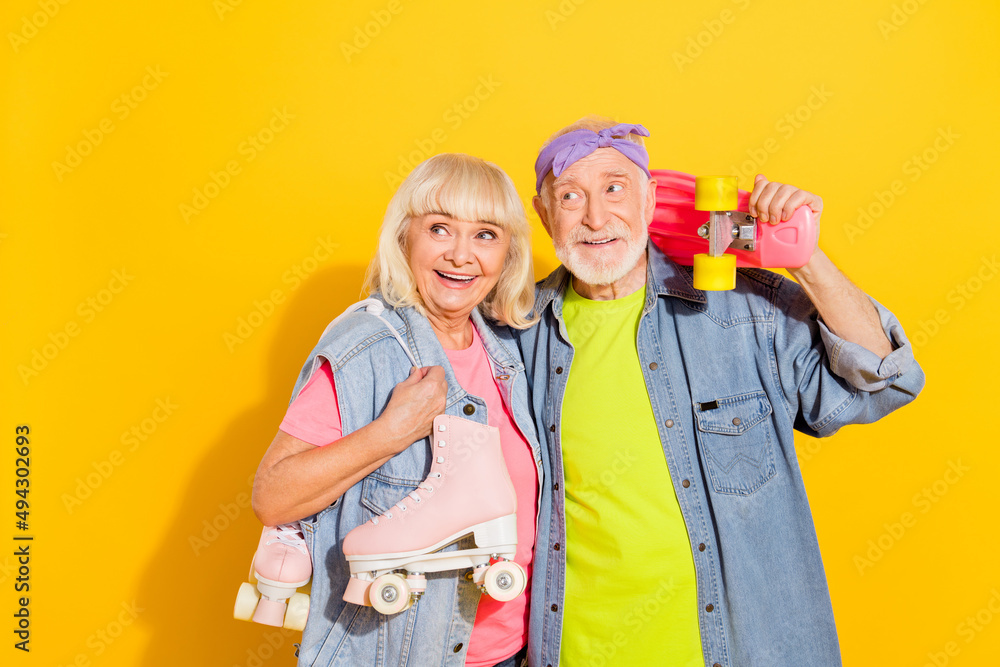 Photo of pretty thoughtful husband wife wear jeans shirts holding rollers long board empty space isolated yellow color background Photo of pretty thoughtful husband wife wear jeans shirts holding rollers long board empty space isolated yellow color background