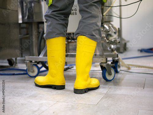 Legs of a worker with vivid yellow boots in a craft beer brewery