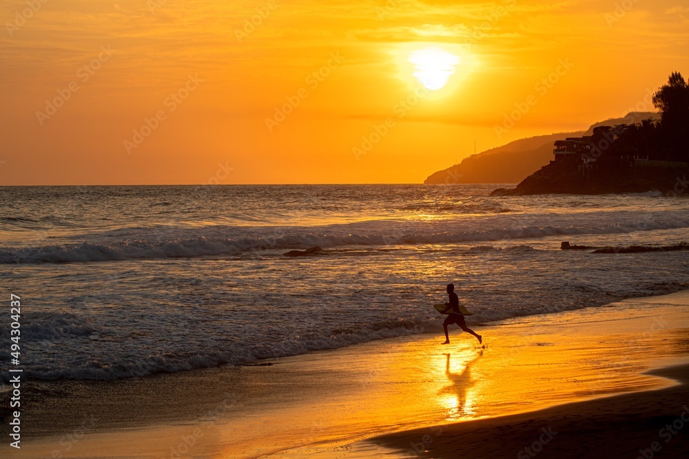 A view of a surfer during a colorful sunset on the beach in El Zonte in El Salvador. Surf City.