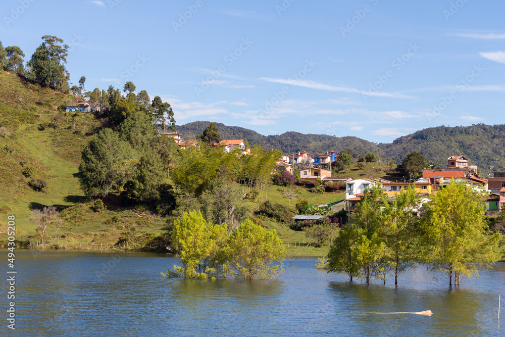 View of the beautiful hills of Guatape, Colombia, with trees growing in the water.
