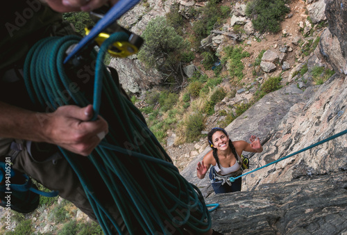Adventurous couple happily rock climbing outdoors