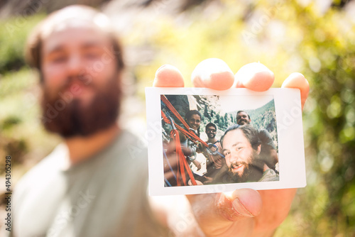 Friendly man holding up and showing polaroid of climbing friends
