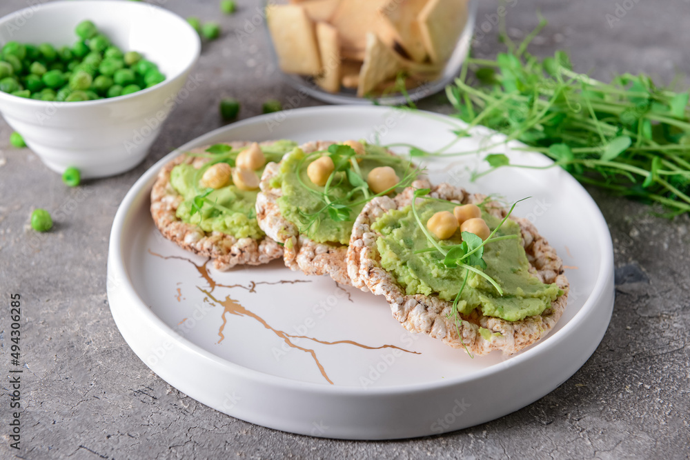Plate with crispbreads and tasty pea hummus on grunge background Plate with crispbreads and tasty pea hummus on grunge background