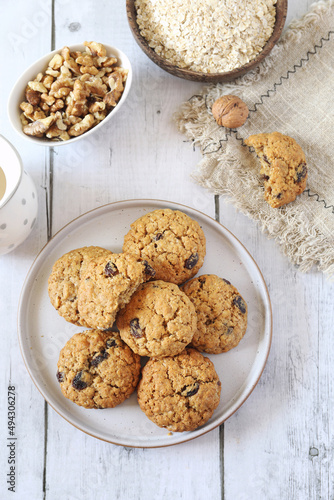 Homemade oatmeal cookies with raisins and walnuts on light background