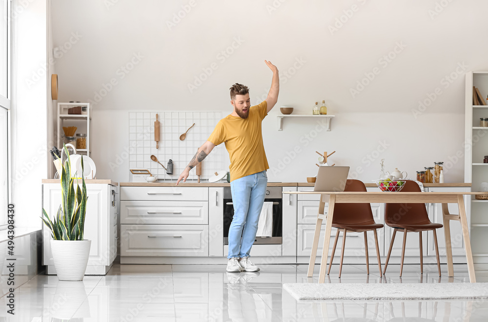 Cool young man with laptop learning to dance at home Cool young man with laptop learning to dance at home