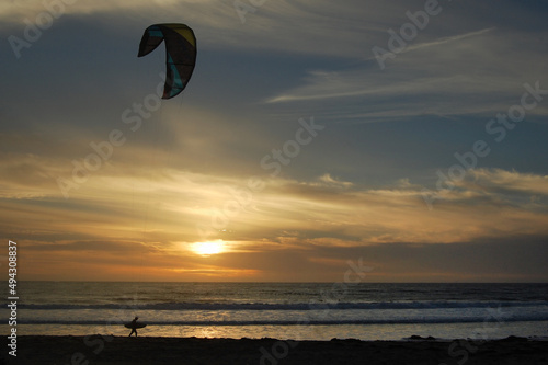 A kiteboarder walking along the beach at sunset, Lompoc, Santa Barbara County, California.