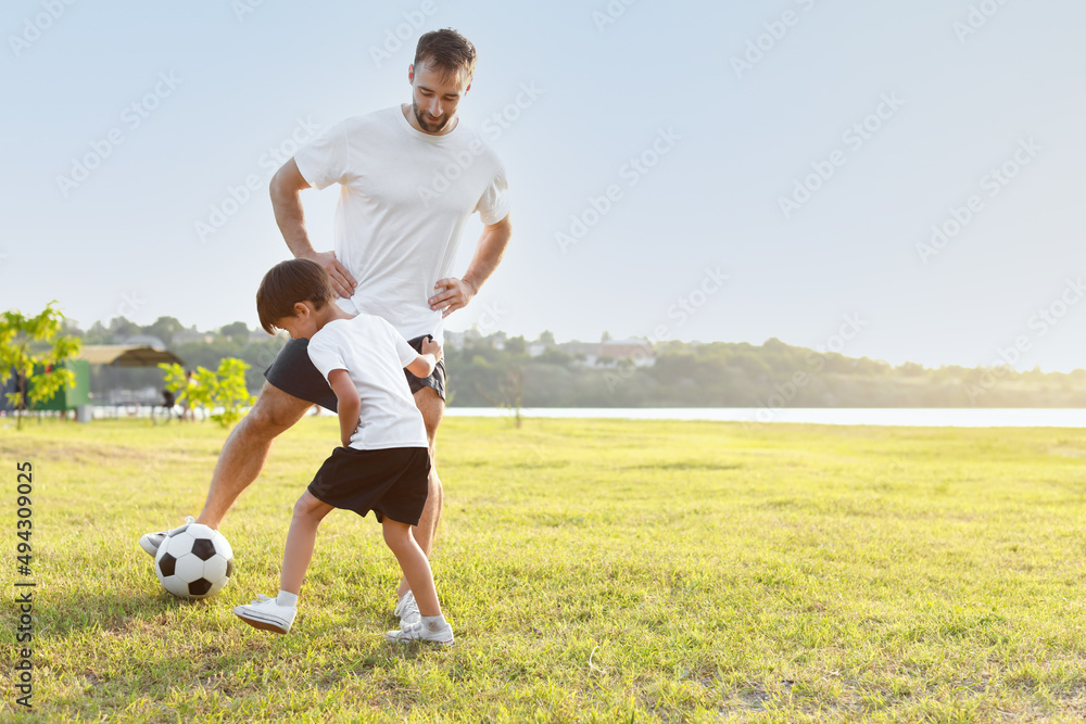 Little boy playing soccer with his father on field Little boy playing soccer with his father on field