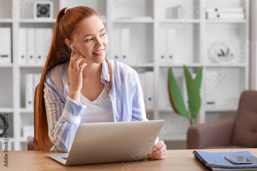 Young woman with laptop listening to music at home