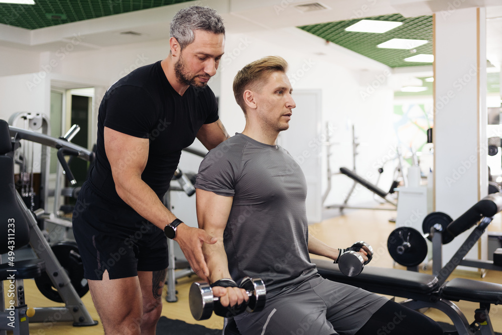 Obraz premium A personal trainer motivates the client to do push-ups in the gym. Personal workout hour with personal coach