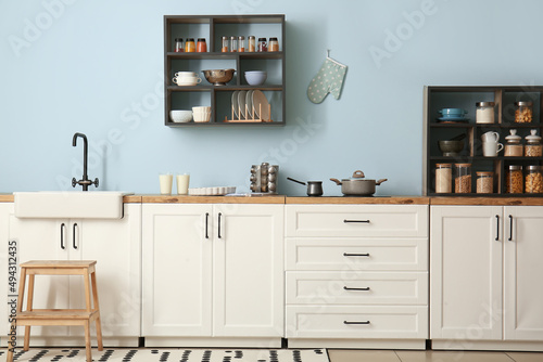 Interior of stylish kitchen with white counters, shelves and supplies © Pixel-Shot