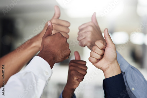 We say yes to success. Shot of a group of unidentifiable businesspeople showing thumbs up in the office.