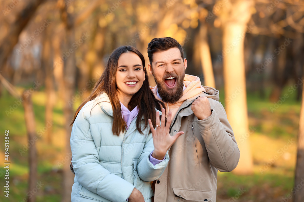 Fototapeta premium Happy young woman with engagement ring and her fiance in forest