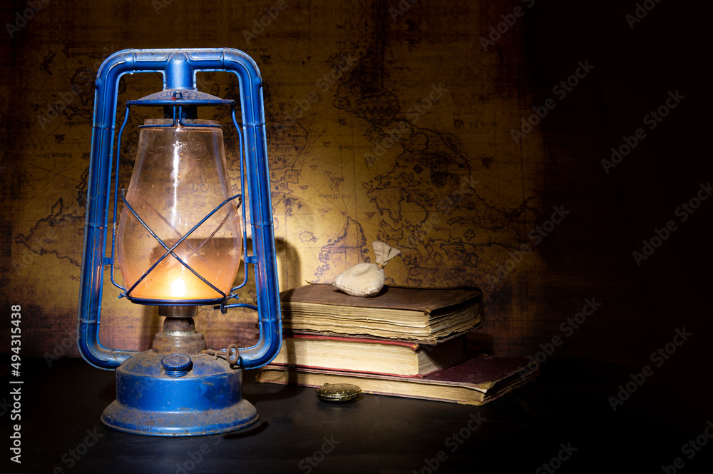 Vintage kerosene lamp oil lantern burning with books - study concept