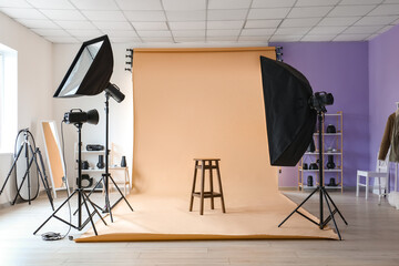 Lighting equipment, stool and beige cyclorama in modern photo studio