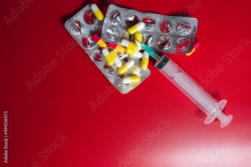 medical pills with srynge on red background photo