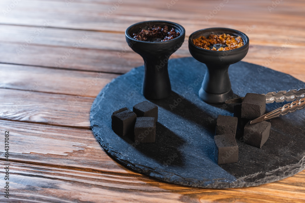 Tweezers near coals and hookah bowls on wooden surface. Tweezers near coals and hookah bowls on wooden surface.