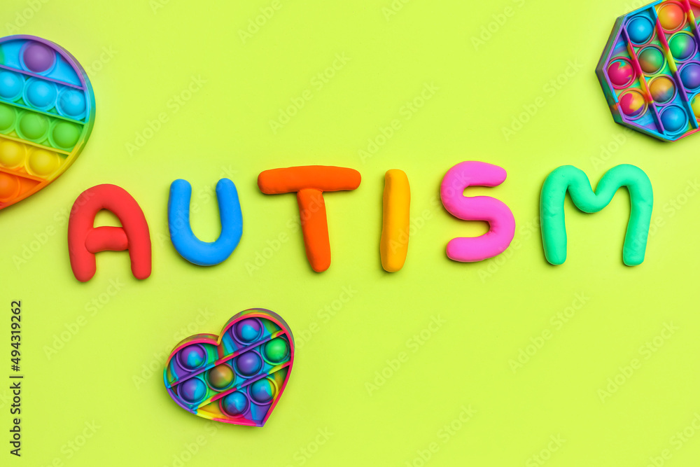 Word AUTISM with pop it fidget toys on green background