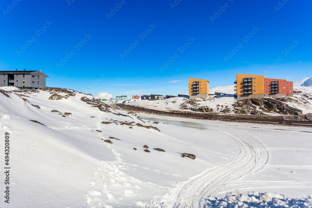Greenlandic landscape with Inuit multistory houses of Nuuk city on the rocks with mountains in the background, Greenland