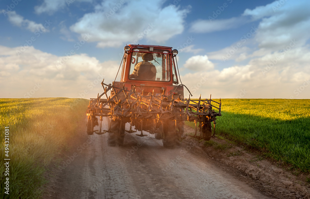 Obraz premium tractor on the road after working on the farm on sunset. Silhouette of old tractor in country road on the way to home.