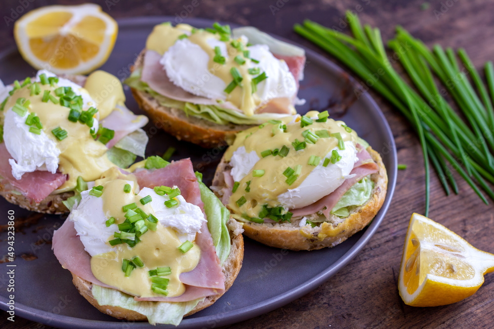Sandwiches with poached egg, ham, lettuce, and chives, topped with sauce. Eggs Benedict
