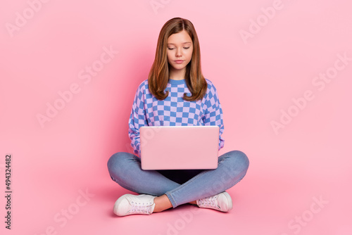 Full length photo of brown hairdo teenager girl sit write laptop wear sweater jeans shoes isolated on pink background