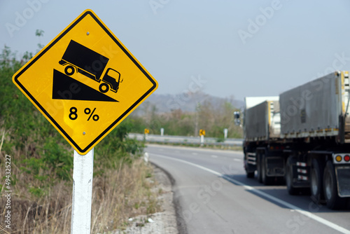 Yellow traffic sign to warn truck driver to drive carefully down to hill on slope a steep 8 percent(8%) downhill gradient beside the road. Concept : Traffic Road Sign and symbol.