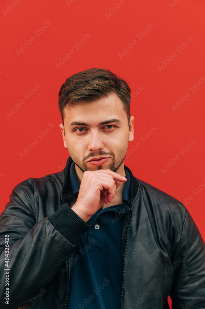 Portrait of adult handsome man with bristles in smoker on red wall background, posing at camera, vertical Portrait of adult handsome man with bristles in smoker on red wall background, posing at camera, vertical