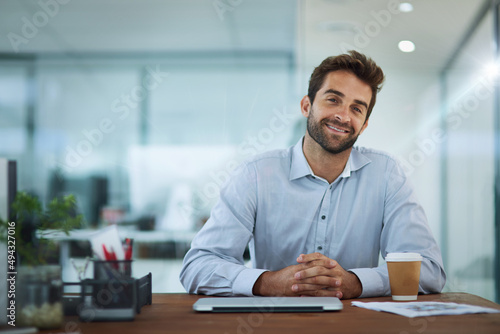 Relaxed and productive. Portrait of a young corporate businessman sitting at a desk in an office.