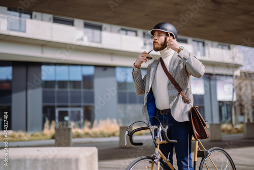 Young businessman is putting on helmet before bicycle ride.Travel to work. Safety and eco friendly transport photo