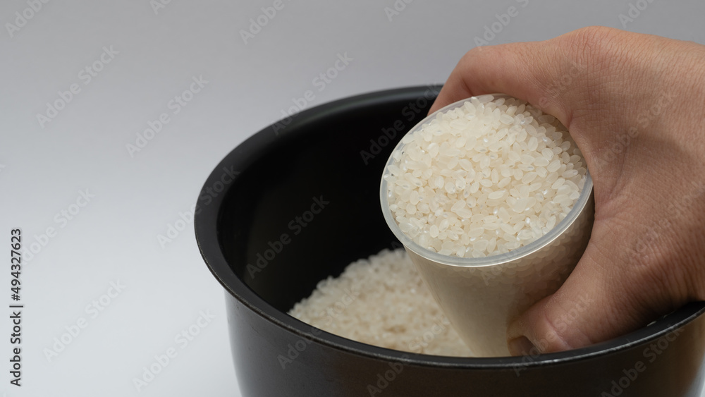 計量カップで白米を炊飯ジャーの内釜に入れるシーン