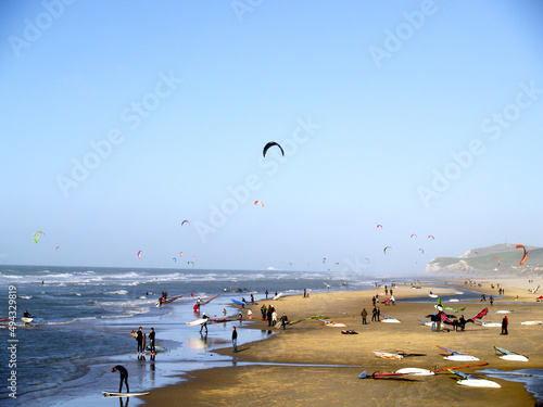 Photography View of a beach in summertme with people surfing and paragliding on their vacati