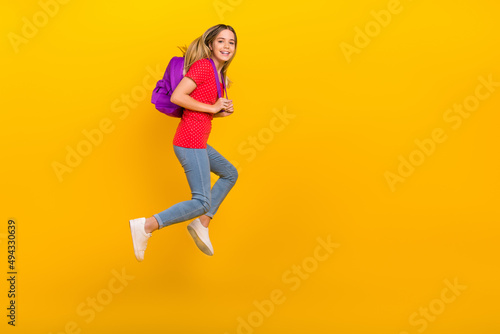Full body profile side photo of young active girl runner walk hold bag courses isolated over yellow color background