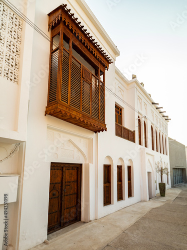 Vertical shot of white-walled buildings with wooden mashrabiya balconies photo