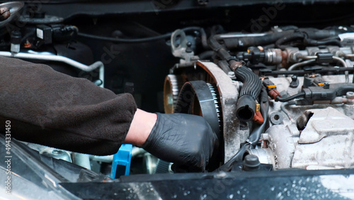 Replacing the engine timing belt in an automobile. Auto mechanic in a car repair center. Replacement of automobile oil and filter