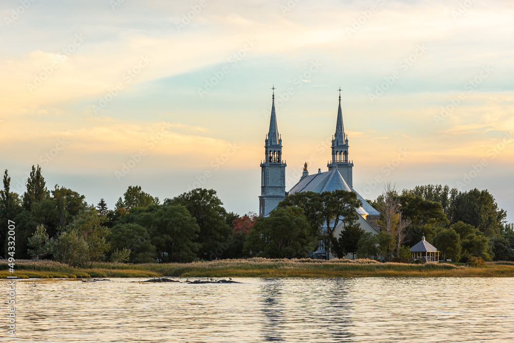 The church of Saint-Roch-des-Aulnaies at the sunset with the St. Lawrence river in the foreground (Saint-Roch-des-Aulnaies, Quebec, Canada)