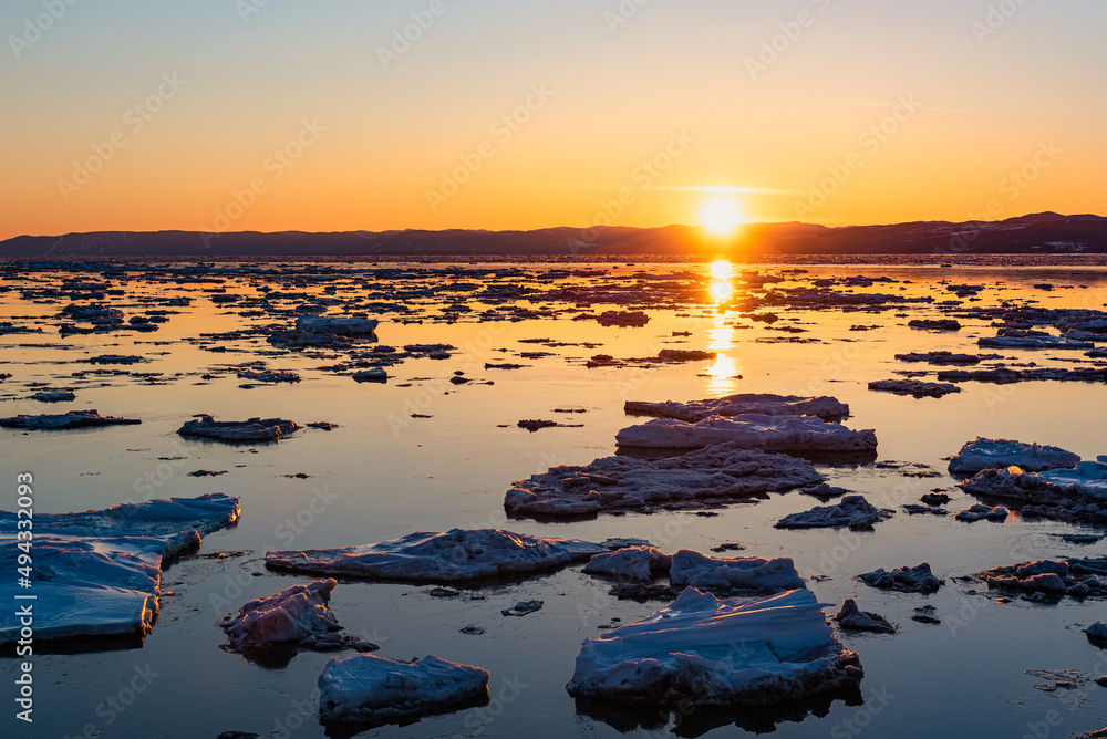 Naklejka premium At the sunset, floting ice on the Saint-Lawrence river at Rivière-Ouelle in the Kamouraska (Quebec, Canada).