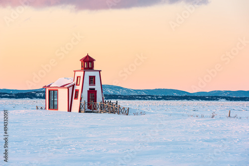 Winter's view of the little lighthouse of Saint-Andre-de-Kamouraska with ice on Saint-Lawrence river and the Charlevoix in background (Quebec, Canada). photo