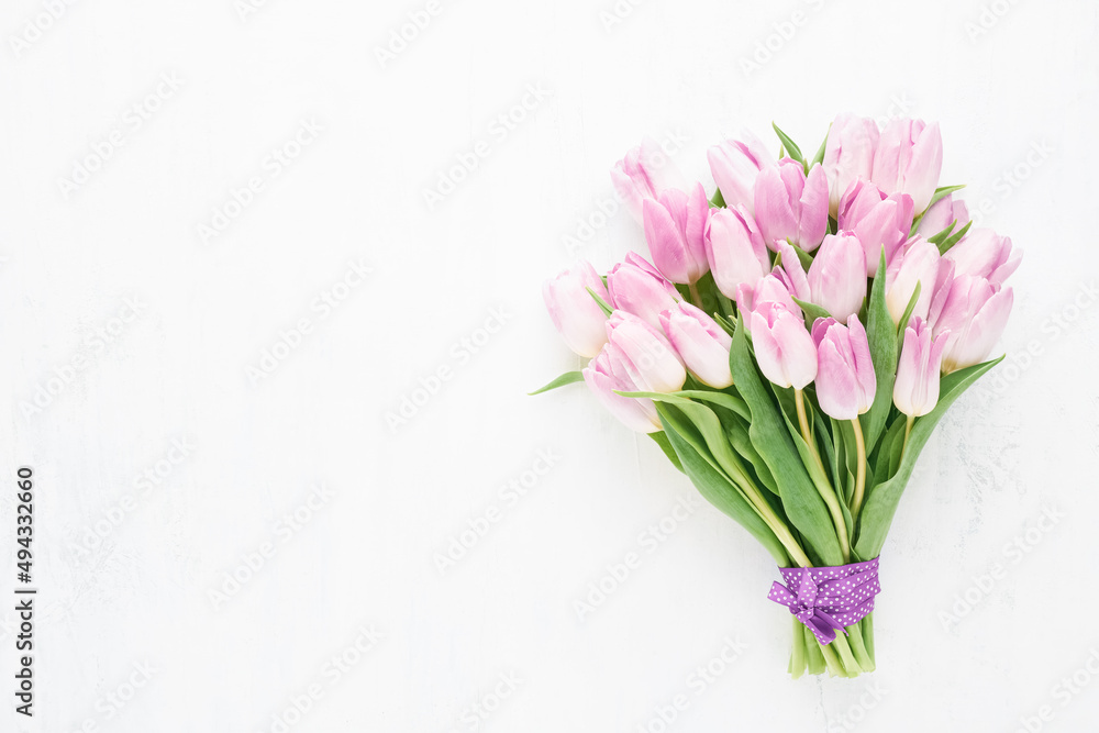 Pink tulips bunch decorated with ribbon on a white wooden background. Mothers Day card Pink tulips bunch decorated with ribbon on a white wooden background. Mothers Day card