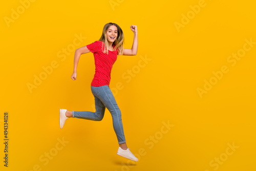 Full size profile side photo of young girl runner hurry motion speed jump discount isolated over yellow color background