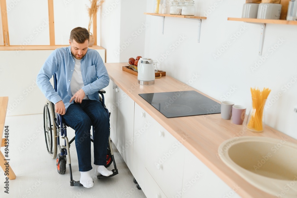 Young Disabled Man On Wheelchair In The Kitchen Young Disabled Man On Wheelchair In The Kitchen