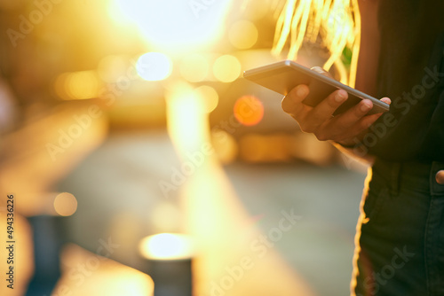 Meet me in the city. Cropped shot of an unrecognizable young woman sending a text while walking around the city.