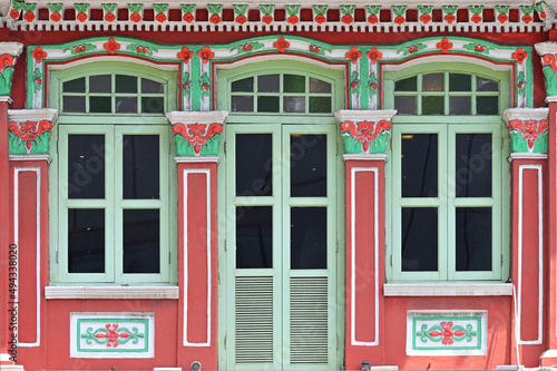Maroon green Straits Chinese Peranakan shophouse with arched windows, wooden louvers, ornate columns photo