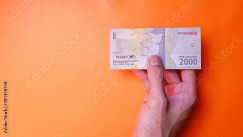 Indonesian Rupiah the official currency of Indonesia. Man's hand is making a payment. Male hand showing Indonesian Rupiah note. Business Investment Economy and Finance concept. Uang 2.000 2000 Rupiah