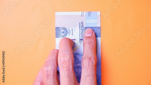 Indonesian Rupiah the official currency of Indonesia. Man's hand is making a payment. Male hand showing Indonesian Rupiah note. Business Investment Economy Loan and Finance concept. Uang 50.000 Rupiah