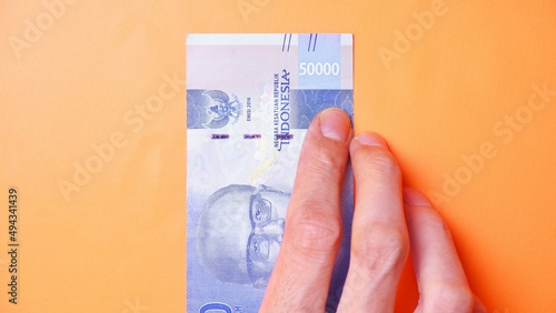 Indonesian Rupiah the official currency of Indonesia. Man's hand is making a payment. Male hand showing Indonesian Rupiah note. Business Investment Economy and Finance concept Uang 50000 50.000 Rupiah
