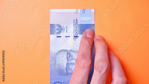 Indonesian Rupiah the official currency of Indonesia. Man's hand is making a payment. Male hand showing Indonesian Rupiah note. Business Investment Economy and Finance concept Uang 50000 50.000 Rupiah