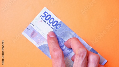 Indonesian Rupiah the official currency of Indonesia. Man's hand is making a payment. Male hand showing Indonesian Rupiah note. Business Investment Economy and Finance concept Uang 50000 50.000 Rupiah